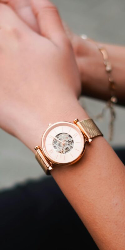 Close-up of a stylish golden wristwatch worn on a woman's wrist, showcasing elegance.